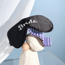 Bride silk eyemask on stacked rocks and purple paper with blue background and white curtain