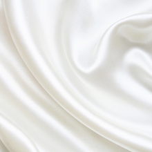 Close-up of smooth silk texture on ivory white pillowcase.