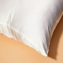 Close-up of corner of Ivory White Cloud 9 Silk Pillowcase pillow with orange background