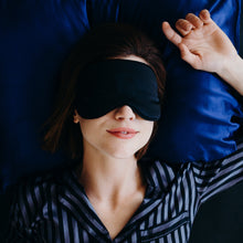 Girl lying on blue bed with soft silk black eyemask