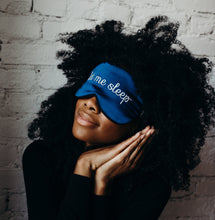Girl with black curly hair in dark top wearing 'Let Me Sleep' Sleeping Silk Eye Mask, making sleep gesture with hands.
