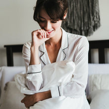 Girl in white silk pajamas smiling while holding a pillow fitted with Cloud 9 Silk Pillowcase in Ivory White.