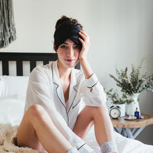 Girl sitting on bed with soft silk black eyemask. 
