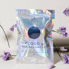 'Cloud 9' Night Sky Navy Blue Silk Pillowcase in iridescent packaging standing upright with purple flowers