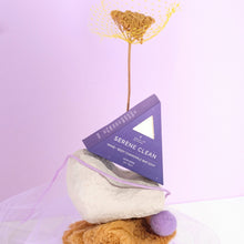 Moonlit Skincare Serene Clean Soap on top of a structure with yellow flower behind it on purple background