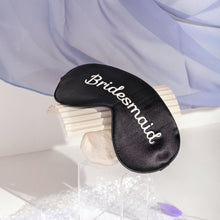 Bridesmaid silk eyemask on white box and paper with white background and purple curtain